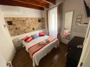 Schlafzimmer mit einem Bett mit roten und blauen Kissen in der Unterkunft Lu Bàtil B&B - Rooms in Alghero