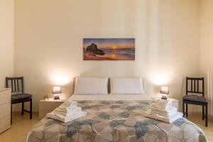 a bedroom with a bed with two chairs and a painting on the wall at Ragusa 59 in Ragusa