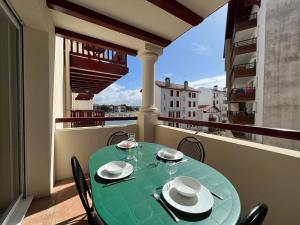 einen Tisch auf einem Balkon mit einem grünen Tisch und Stühlen in der Unterkunft Appartement Ciboure, 3 pièces, 4 personnes - FR-1-239-895 in Ciboure