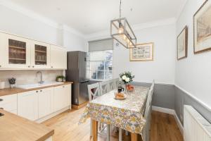 a kitchen with a table and a sink and a refrigerator at 6 Bedroom City Centre Georgian Town House - Abbey & Baths-2 min walk in Bath