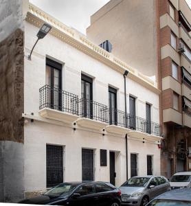 a white building with cars parked in front of it at Apartamentos Loliqui centro Alicante in Alicante
