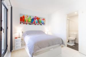 een slaapkamer met een bed en een schilderij van papegaaien bij Old City Penthouse with fantastic views & parking in Benidorm