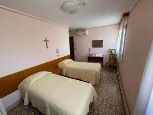 Habitación con 2 camas y una cruz en la pared. en Casa Caburlotto, en Venecia