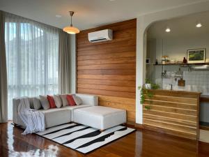 a living room with a white couch and a kitchen at Baan Jai Klang (บ้านใจกลาง) in Chiang Rai