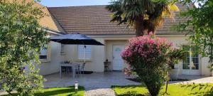 una casa con una mesa y una sombrilla en el patio en A la bonne étape, en Sassenay