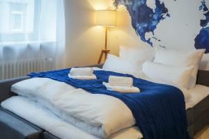 1 cama con almohadas blancas y manta azul en 7SEAS Apartment zentral mit High-Speed Wifi für 4 P, en Kaiserslautern