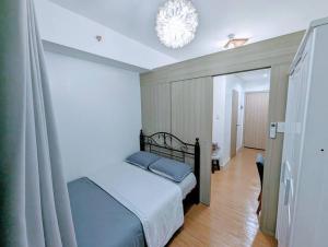 a bedroom with a bed and a chandelier at Love@Grace Residences near BGC. in Manila