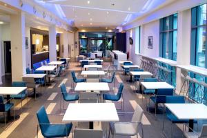a cafeteria with tables and chairs and windows at Holiday Inn Express Manchester City Centre Arena by IHG in Manchester