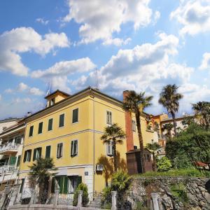 une maison jaune avec des palmiers devant dans l'établissement Elegance Suite - "100m from the Beach with Free Parking and Garden", à Opatija