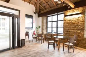 a dining room with tables and chairs and a stone wall at Hotel Casa da Luz in Pastoriza
