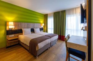 Una habitación de hotel con una cama con una pared de acento verde en Kedi Hotel Papenburg en Papenburg