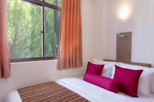 a bedroom with a bed with red pillows and a window at Beehive Central in Male City