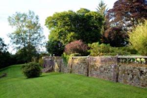 a garden with a stone fence and green grass at Mabie House Hotel in Dumfries