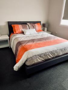 een slaapkamer met een groot bed met oranje en bruine kussens bij Kulin Erindale Apartments in Kulin