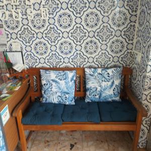 eine Holzbank mit zwei Kissen und einer Wand in der Unterkunft Guest House Pacifica in Quarteira