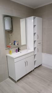 a white bathroom with a sink and a mirror at Grand Apartman in Živinice