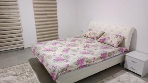 a bedroom with a white bed with pink flowers at Grand Apartman in Živinice