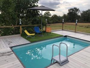 a swimming pool with two chairs and an umbrella at The Yurt at Les Forges in Saint-Sornin-la-Marche