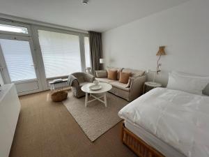 een slaapkamer met een bed, een bank en een tafel bij Haus Janus 3 - Wohnung 2 in Norderney