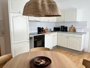 een keuken met witte kasten en een houten tafel bij Haus Janus 3 - Wohnung 2 in Norderney