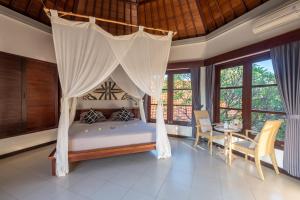 a bedroom with a canopy bed with a table and chairs at Villa Santai Pemuteran in Pemuteran +37 photos