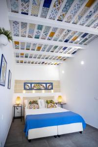 Schlafzimmer mit einem Bett mit blauer und weißer Decke in der Unterkunft Acquarò Suite Jacuzzi in San Vito lo Capo