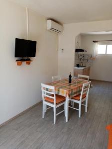 uma sala de jantar com uma mesa com cadeiras e uma televisão em Seafront Apartment Dana em Vela Luka