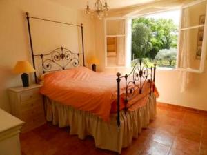 a bedroom with a bed with an orange bedspread and a window at Villa spacieuse avec piscine à Saint-Michel-d'Euzet in Saint-Michel-d'Euzet +27 photos