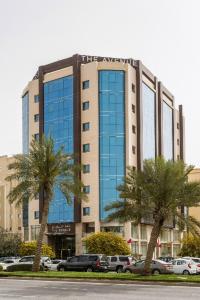 un edificio alto con palmeras delante en The Avenue Hotel, en Doha