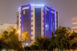 a building with a blue lit up sign on it at The Avenue Hotel in Doha