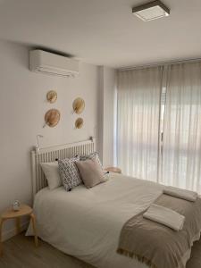 een witte slaapkamer met een groot bed en een raam bij Ameyal Casa PIO XII in Sanlúcar de Barrameda