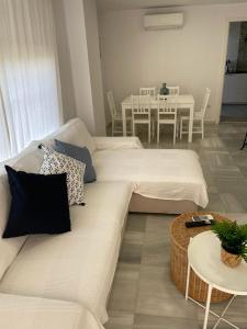 een woonkamer met een witte bank en een tafel bij Ameyal Casa PIO XII in Sanlúcar de Barrameda