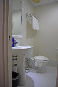 馬尼拉的住宿－奎松市馬勒卡費薩爾酒店，白色的浴室设有水槽和卫生间。
