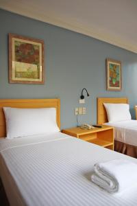 マニラにあるファーサル ホテル マラカス ケソン シティのベッド2台、デスク、ベッド1台が備わるホテルルームです。