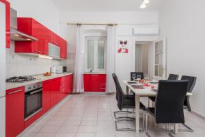 Apartment Dana في رييكا: مطبخ مع دواليب حمراء وطاولة مع كراسي
