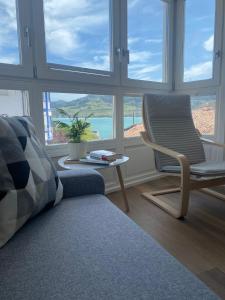 a living room with a chair and a table and windows at APARTAMENTOS ARATUSTE - News a estrenar in Mundaka