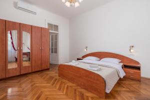 Apartment Dana في رييكا: غرفة نوم مع سرير خشبي كبير ومرآة