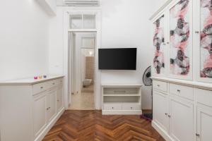 a kitchen with white cabinets and a flat screen tv at Apartment Dana in Rijeka