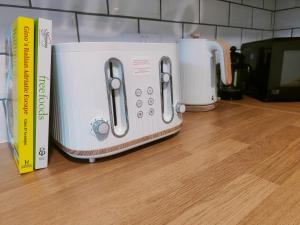 a white toaster sitting on a counter next to books at Cosy Home in Historical Beverley Town with Parking in Beverley