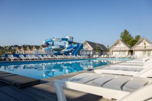 a swimming pool with chairs and a water slide at Holiday Park & Resort Ustronie Morskie in Ustronie Morskie
