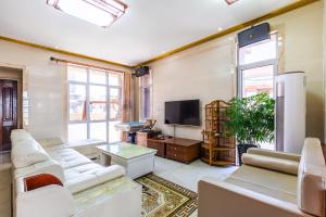 ein Wohnzimmer mit weißen Möbeln und einem Flachbild-TV in der Unterkunft Fancy Apartment in Suizhong