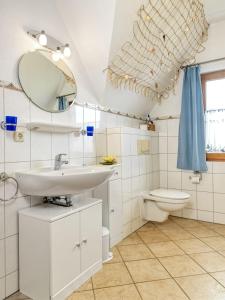 ein Badezimmer mit einem Waschbecken, einem WC und einem Spiegel in der Unterkunft Reethus Blinkfüer in Timmendorf