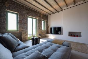 a living room with a couch and a brick wall at Kalma Living Luxury Villas in Kithnos