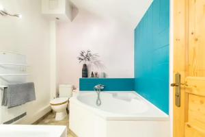 een badkamer met een wit bad en een toilet bij La Parenthèse, chambres d'hôtes in Rochegude