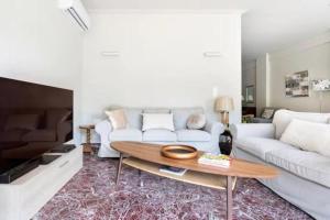 a living room with a white couch and a table at Flisvos Marina refurbished apartment in Athens