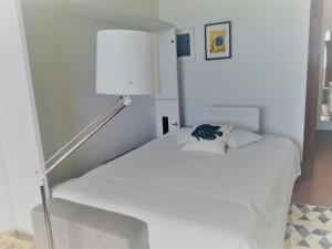 a bedroom with a white bed and a lamp at Troia MaisMais apartamento in Troia