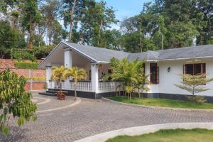 a white house with palm trees in front of it at StayVista at The Haven - Grandeur with Breakfast & BBQ Grill in Madikeri