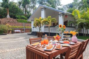 einen Holztisch mit Essen auf einer Terrasse in der Unterkunft StayVista at The Haven - Grandeur with Breakfast & BBQ Grill in Madikeri