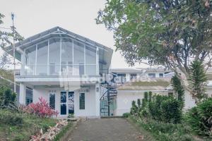 a white house with a glass facade at Villa Puncak Agape near Cipanas Mitra RedDoorz in Cianjur