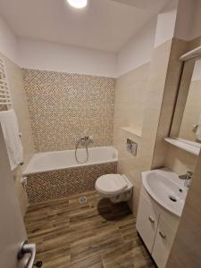 a bathroom with a tub and a toilet and a sink at G!RO Guest House in Sfântu-Gheorghe